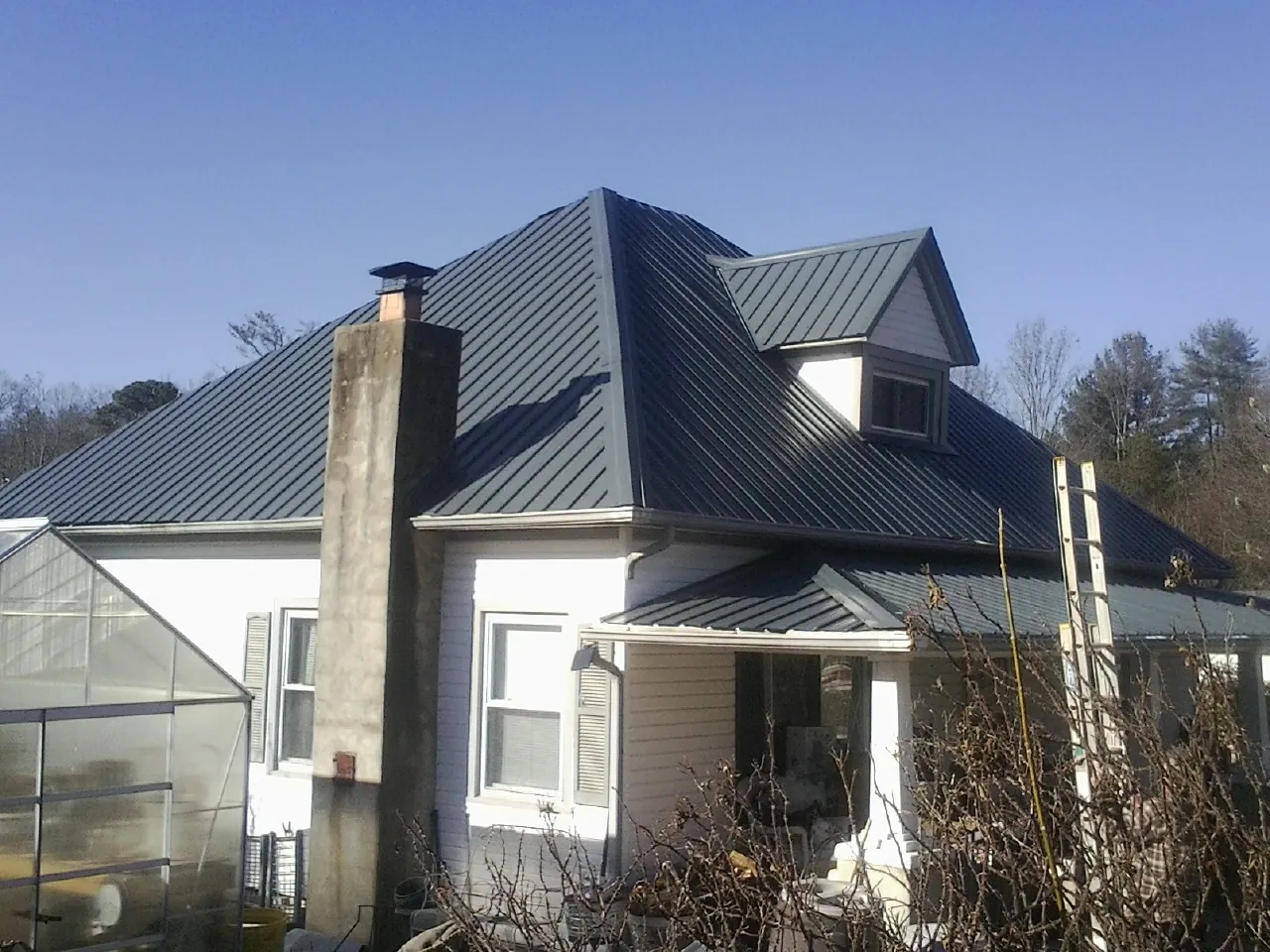 Dark blue standing seam metal roof on a white farmhouse with dormer — Slate & Tile Roof Repair by Roofing Brothers in Nokesville
