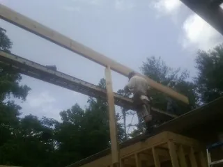 Carpenter setting a ridge beam over a new addition frame — Ice Dam Removal by Roofing Brothers in Nokesville