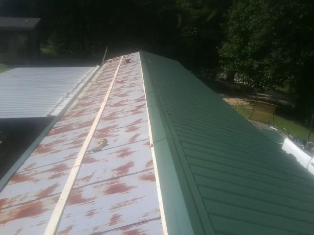 Old rusted panels beside newly installed green metal roofing — Wind Damage Roof Repair by Roofing Brothers in Nokesville