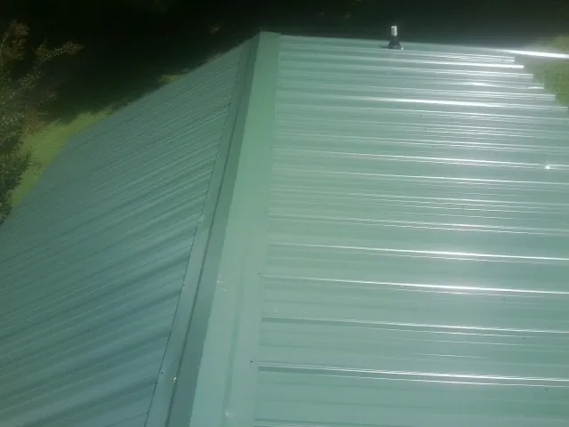 New green metal panels meeting at the ridge of a roof — Flat Roof Repair work by our crew in Nokesville