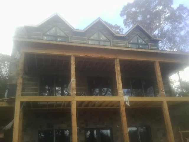 Dormers and porch framing on a large log home under construction — Roof Coating work by our crew in Nokesville