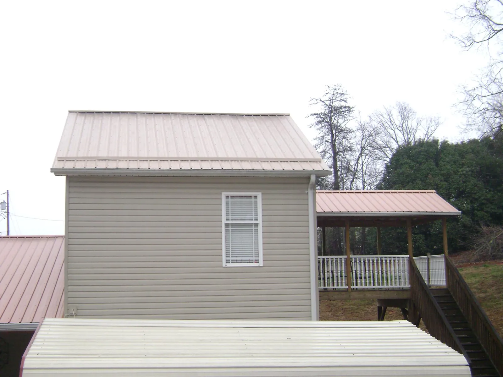 Tan metal roofs on a two story addition and attached porch, from a Roof Replacement job in Nokesville