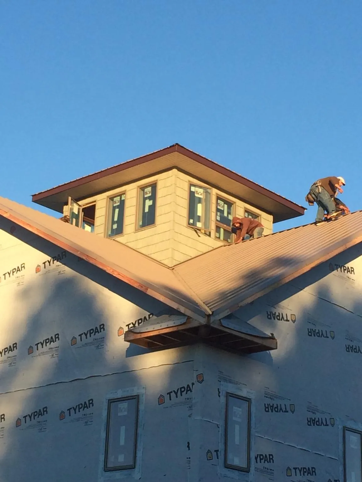 Roofers working around a rooftop cupola on a new metal roof at sunset — Roof Waterproofing in Nokesville by Roofing Brothers